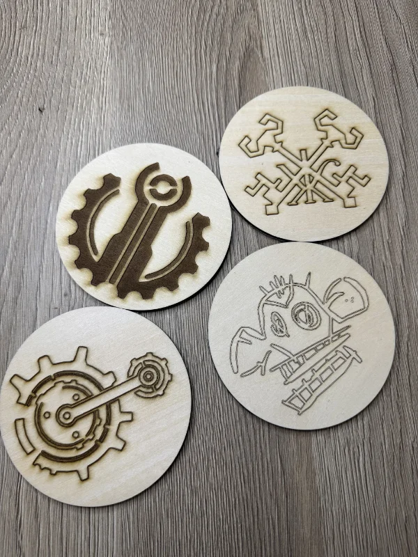 Quatre rondelles en bois avec des motifs découpés : ancre, dentelle, horloge et poisson