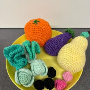 Assortiment de fruits et légumes en crochet colorés sur un plat jaune