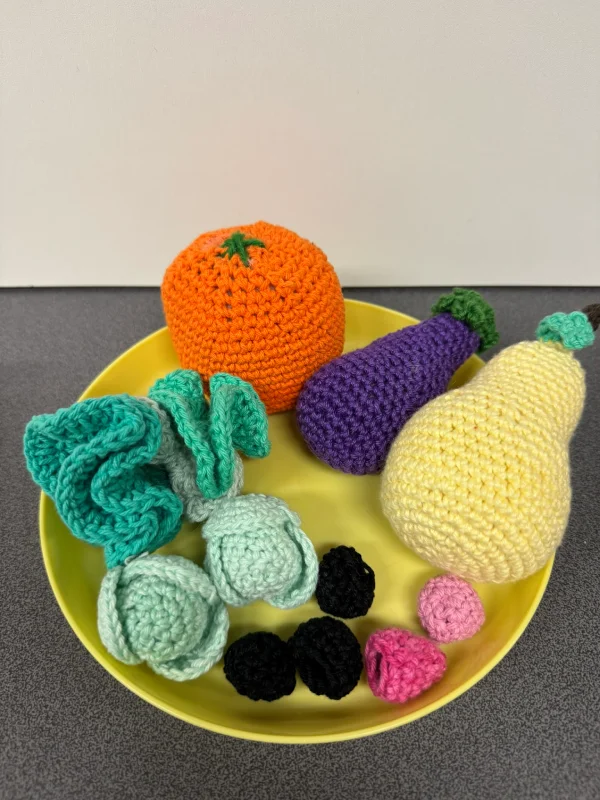 Assortiment de fruits et légumes en crochet colorés sur un plat jaune