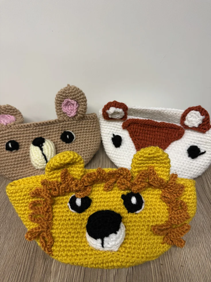 Trois paniers crochetés en forme de têtes d'animaux : lion, ours et vache.