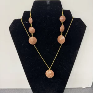 Bijou en or avec des perles roses sur un présentoir noir