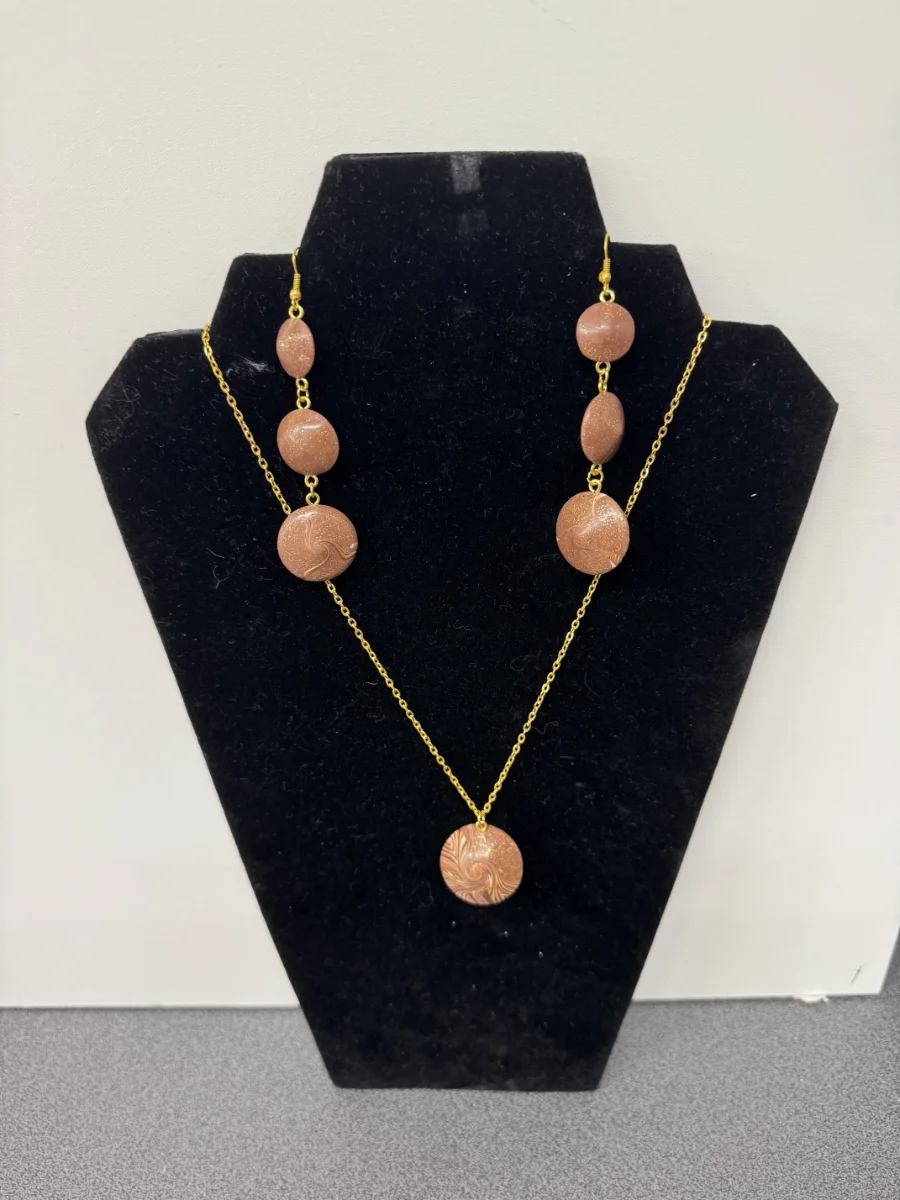 Bijou en or avec des perles roses sur un présentoir noir