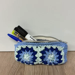 Pochette crochetée bleue et verte avec des fleurs, contenant des stylos et un marqueur.
