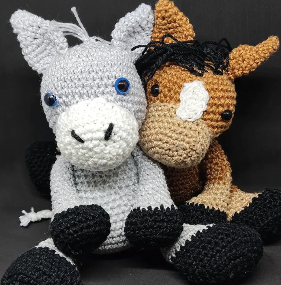 Deux amigurumis, un âne et un cheval, en crochet, contre fond noir