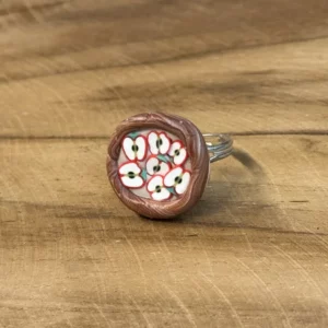 Dernière gourmandise de la série : cette bague reproduit une tarte aux pommes miniature, avec de fines lamelles disposées en éventail sur le dôme, comme une vraie tarte tout juste sortie du four. La bordure façon pâte torsadée, ici en finition argentée, complète l'illusion. Caractéristiques : Dôme façon tarte aux pommes, lamelles modelées à la main Bordure façon pâte torsadée, monture argentée Fait main à Arras Pièce unique Entretien : évitez les frottements répétés et l'exposition prolongée au soleil. Envie d'une autre gourmandise ? Toute la collection est ici.
